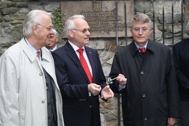 Drei Herren stehen vor dem Dickerturm und halten einen Schlüssel, bereit zur feierlichen Eröffnung. Ein historischer Moment!